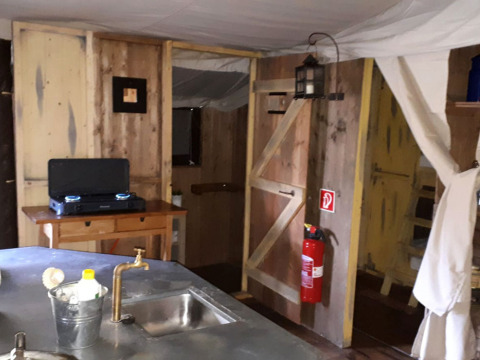 Rustic kitchen at Feather Down Hilserhof, with wooden walls, gas stove, sink, and a fire extinguisher.