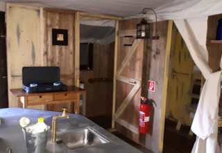 Rustic kitchen at Feather Down Hilserhof, with wooden walls, gas stove, sink, and a fire extinguisher.