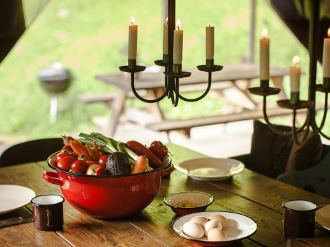 Légumes frais et œufs disposés sur une table rustique éclairée à la bougie à Feather Down Hilserhof, Allemagne.