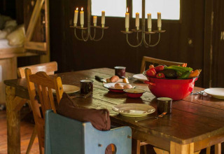 Tavolo rustico con sedie in legno, candelabro e verdure fresche in ciotola rossa a Feather Down Hilserhof.