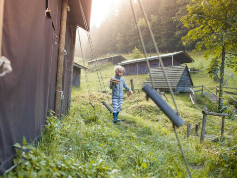 Un enfant marche dans l’herbe près des tentes au Feather Down Hilserhof, parc de vacances à Baden-Württemberg, Allemagne.