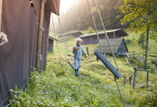 Un enfant marche dans l’herbe près des tentes au Feather Down Hilserhof, parc de vacances à Baden-Württemberg, Allemagne.
