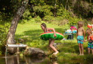 Bambini giocano con ciambelle e braccioli vicino all'acqua al Feather Down Hilserhof in Germania.