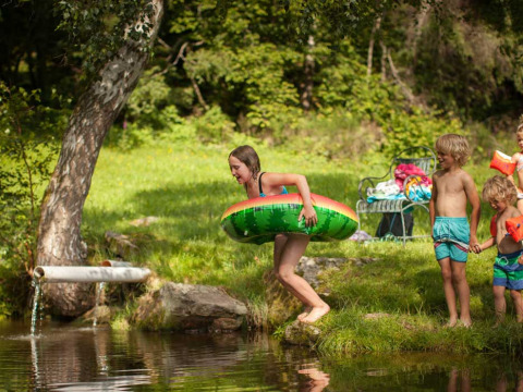 Niños juegan con flotadores y manguitos cerca del agua en Feather Down Hilserhof, Baden-Württemberg, Alemania.