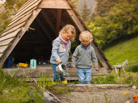 Twee kinderen spelen buiten een houten hut bij Feather Down Hilserhof, Baden-Württemberg, Duitsland.
