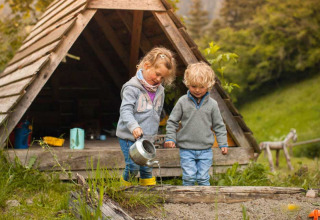 Due bambini giocano fuori da una capanna di legno a Feather Down Hilserhof, Baden-Württemberg, Germania.