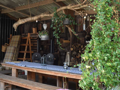Zona de descanso exterior con bancos y mesa de madera decorada con plantas en De Kalverweide, Overijssel, Países Bajos.