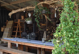 Outdoor seating area with wooden benches, table, and plants at Feather Down De Kalverweide, Overijssel, Netherlands.