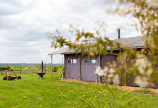 Uitzicht op een tent bij Feather Down De Kalverweide vakantiepark in Overijssel, Nederland, met groene velden.