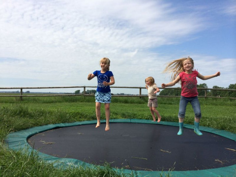 Tres niños saltan en una cama elástica en Feather Down De Kalverweide, un parque vacacional en Overijssel, Países Bajos.