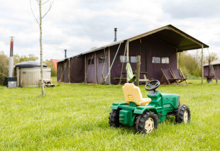 Speelgoedtractor op het gras voor een safaritent bij Feather Down De Kalverweide, Overijssel, Nederland.