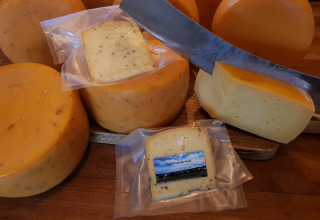 Cheese wheels and vacuum-packed cheese slices on wooden board, taken at Feather Down De Kalverweide, Netherlands.