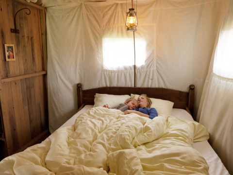 Una madre y su hijo duermen juntos en una cama acogedora con sábanas blancas en Feather Down Glastonbury Hill Farm.