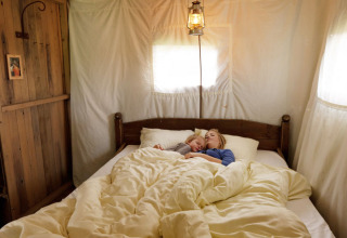En mor og et barn sover sammen i en hyggelig seng med hvide dyner på Feather Down Glastonbury Hill Farm.