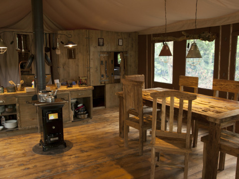 Interior rústico de cabaña en Feather Down Glastonbury Hill Farm con muebles de madera y estufa.
