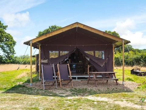 Tienda de campaña con sillas y mesa de picnic en Feather Down Glastonbury Hill Farm, Sudoeste de Inglaterra.
