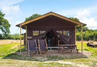 Udendørs teltlodge med træmøbler på Feather Down Glastonbury Hill Farm, en feriepark i Sydvestengland.