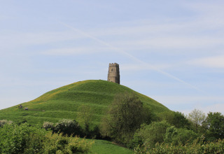 Blick auf Glastonbury Tor mit St. Michaels Turm auf einem grünen Hügel bei Feather Down Glastonbury Hill Farm.