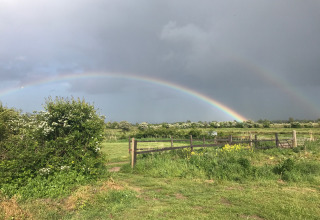 Dubbele regenboog boven de weiden bij Feather Down College Farm, vakantiepark in Oost-Engeland, VK.