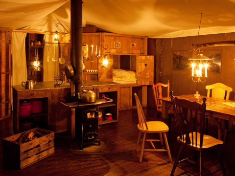 Intérieur chaleureux avec poêle à bois, meubles rustiques et éclairage doux à Feather Down College Farm.