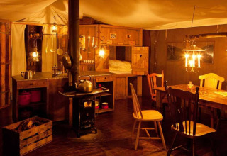 Gemütliches Innenraumfoto mit Holzofen, rustikalem Tisch und warmem Licht in Feather Down College Farm.