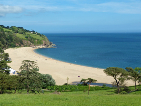 View of the sandy beach and blue sea at Feather Down Fountain Violet Farm in South West England, UK.