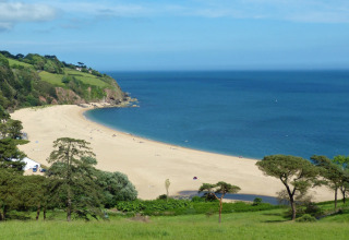 Blick auf einen Sandstrand und das blaue Meer bei Feather Down Fountain Violet Farm in Südwestengland.