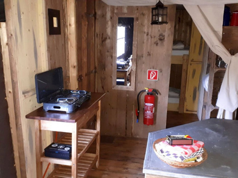 Landelijk houten interieur met fornuis, brandblusser en slaapgedeelte op Fountain Violet Farm.