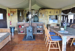 Interno accogliente di tenda a Feather Down Fountain Violet Farm con mobili in legno e stufa.