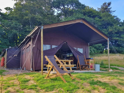 Grote safaritent met houten stoelen bij Feather Down Fountain Violet Farm in Zuidwest-Engeland, Verenigd Koninkrijk.