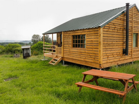 Houten chalet met veranda en picknickbank bij Feather Down Hollings Hill, West Midlands, Verenigd Koninkrijk.