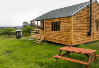 Houten chalet met veranda en picknickbank bij Feather Down Hollings Hill, West Midlands, Verenigd Koninkrijk.