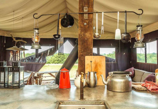 Buitenkeuken in safaritent met waterketel, lantaarns en keukengerei bij Feather Down Hollings Hill, VK.
