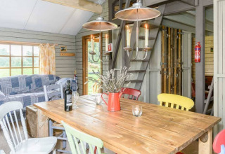 Lichte, landelijke eetruimte met houten tafel, gekleurde stoelen en zicht op Feather Down Hollings Hill.