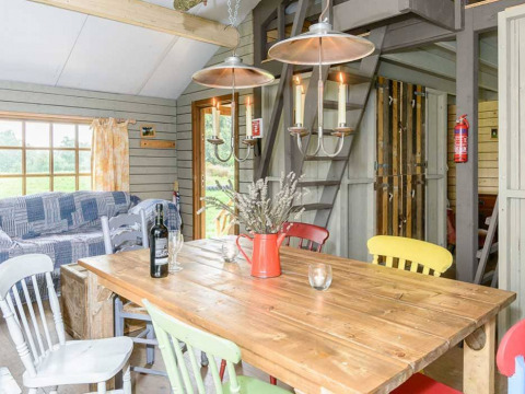 Heldere, rustieke eethoek met houten tafel, kleurrijke stoelen en uitzicht bij Feather Down Hollings Hill.