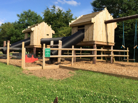 Parque infantil con cabañas de madera, toboganes tubulares y columpios en Feather Down Warren Farm en el suroeste de Inglaterra.
