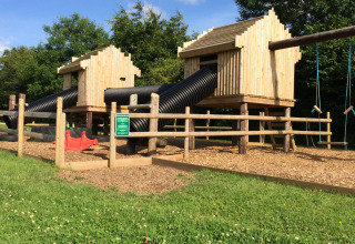 Speeltuin met houten speelhuisjes, buisglijbanen en schommels op Feather Down Warren Farm in Zuidwest-Engeland.