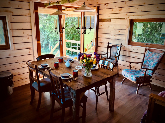 Landelijke houten eetkamer met gedekte tafel en bloemen bij Feather Down Warren Farm, Zuidwest-Engeland.