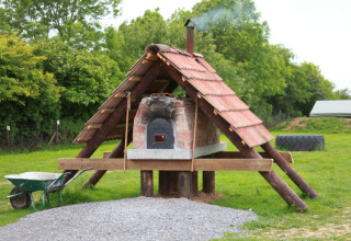 Buitenoven met pannendak op Feather Down Warren Farm, omgeven door groen gras en bomen in Engeland.