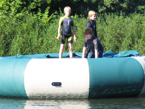 Drie kinderen ravotten op een grote opblaasbare waterstructuur bij Upper Shadymoor Farm in Wales, VK.