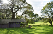 Parco vacanze in Bretagna, Francia, con tenda lodge, sdraio, prato verde e splendida campagna.