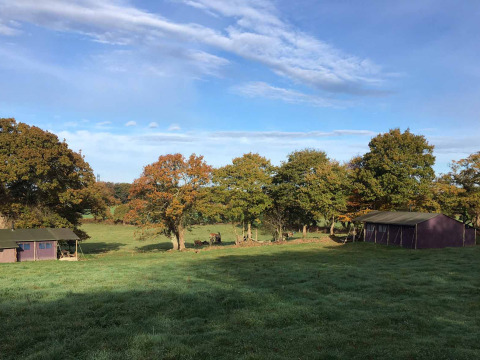 Foto del parque vacacional Feather Down La Ferme de Penquelen Huella en Bretaña, Francia, con tiendas y campo verde.