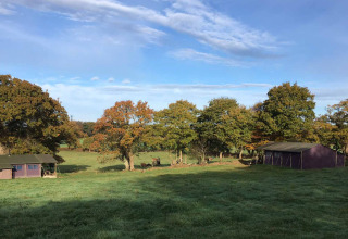 Billede af Feather Down La Ferme de Penquelen Huella feriepark i Bretagne, Frankrig med telte og grønne marker.