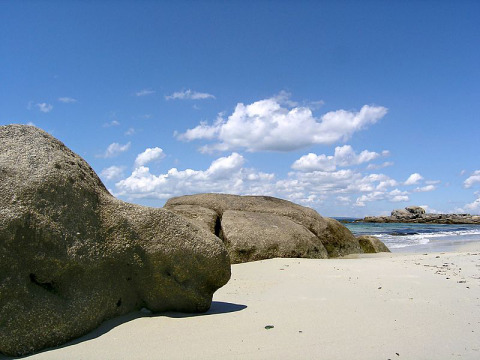 Spiaggia rocciosa e cielo blu con nuvole a Feather Down La Ferme de Penquelen Huella, Bretagna, Francia.