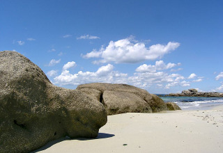 Spiaggia rocciosa e cielo blu con nuvole a Feather Down La Ferme de Penquelen Huella, Bretagna, Francia.
