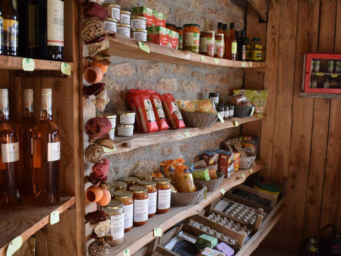 Estantes rústicos con alimentos locales, vinos y conservas en Feather Down La Ferme de Penquelen Huella, Bretaña, Francia.
