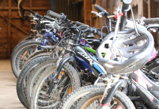 Flere cykler står parkeret indendørs med en cykelhjelm på styret, New Barn Farm, Østengland.