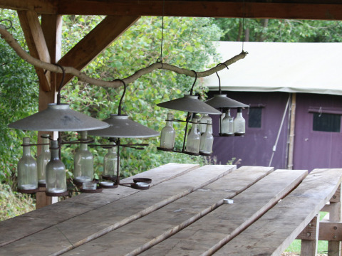 Tavolo in legno con lampade fatte di bottiglie a Feather Down New Barn Farm, parco vacanze nell'Est dell'Inghilterra.