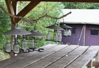 Mesa de madera al aire libre con lámparas de botellas en Feather Down New Barn Farm, parque en el Este de Inglaterra.