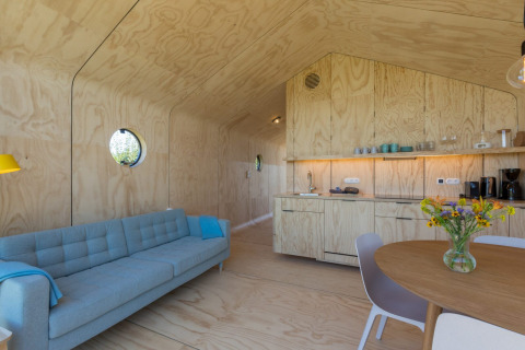 Moderne, lichte vakantiewoning met houten interieur, keuken, ronde ramen en gezellige zithoek in Zeeland.